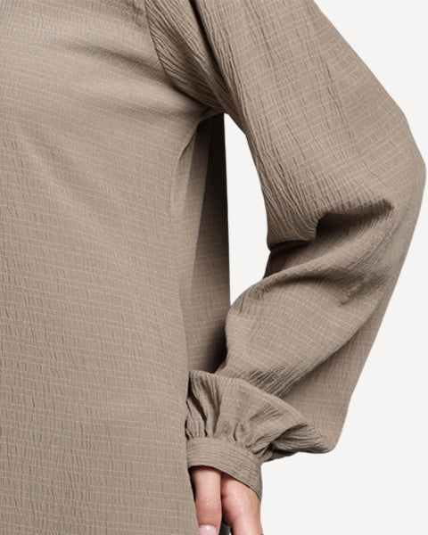 Close-up of a person wearing beige pants with a plain background