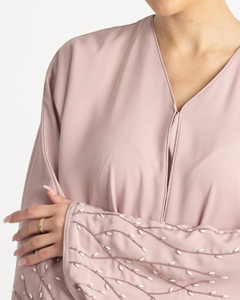 Close-up of a pink dress with beaded sleeves on a white background